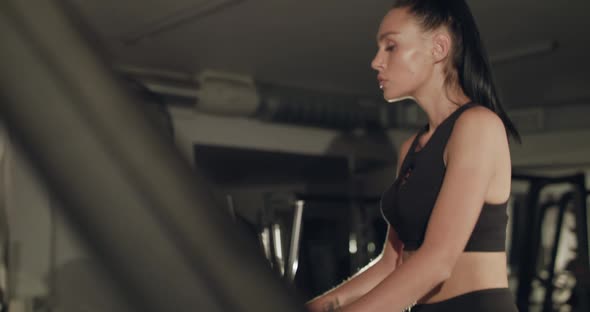 Concentrated Sports Woman with Tied Hair Stepping on a Treadmill in Gym