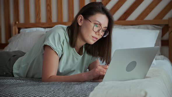 Young Woman Using Laptop Typing Lying on the Bed Remote Work Work at Home