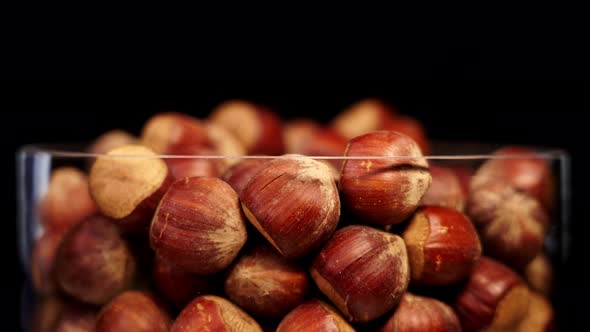 Glass Container with Tasty Edible Hazelnuts Turns on Black