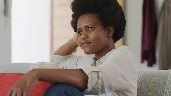 Happy african american woman sitting on sofa in living room