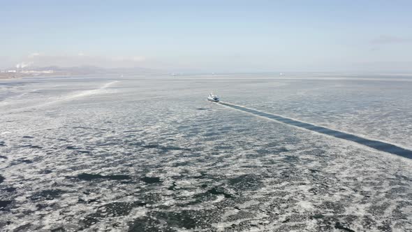 A Ferry Among Ice Floes on a Sunny Day in Winter From a Drone