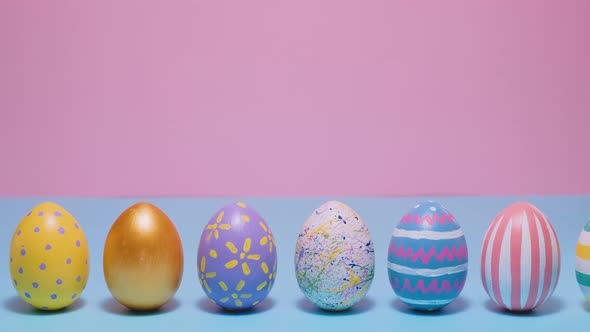 Colorful Easter Eggs Roll and Knock Each Other on a Blue and Pink Background