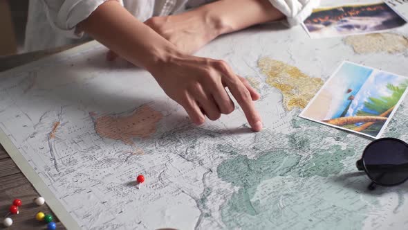 Tourist Vacation Planning With Help World Map With Tourist Accessories Around. Young Woman Pointing