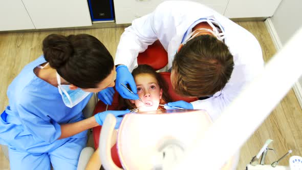 Dentists examining a young patient with tools