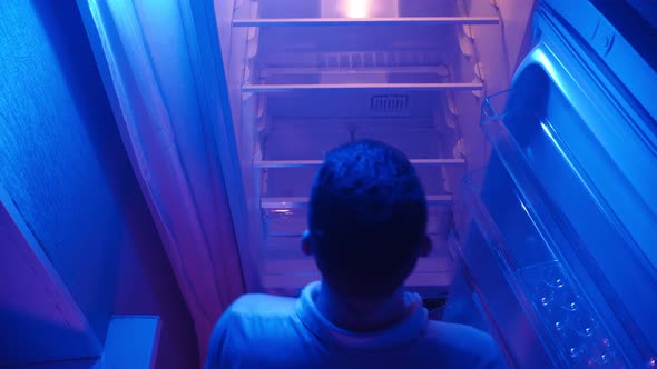 Man Opens Empty Refrigerator at Night in Neon Lighting