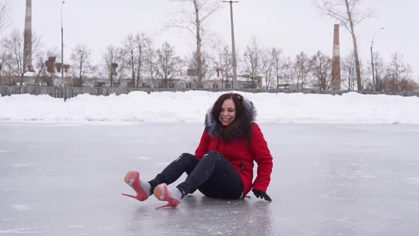 Young Woman in Winter Clothes and Highheeled Shoes Sits on Ice After Fall