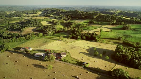 Aerial view of rolling hills and straw bales in field in Correze, France.