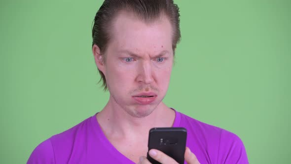 Face of Stressed Young Man Using Phone and Looking Shocked