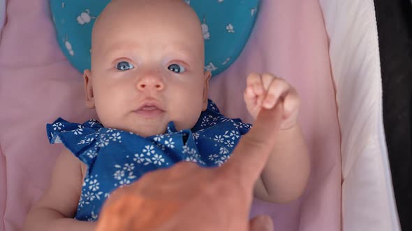 Baby Lying in Pram and Holding Fathers Finger