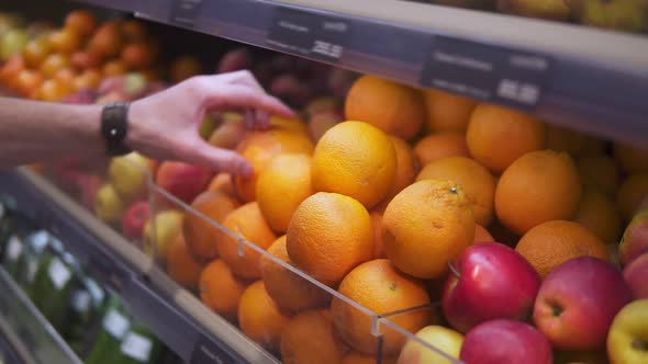 Man's Hand Selecting Fresh Fruits in Grocery Store Produce Department From Shelf