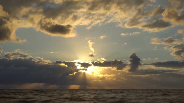 Clouds float above the sea at sunset. Timelapse