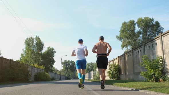 Two Men Are Jogging in an Industrial Area. Runners During a Marathon