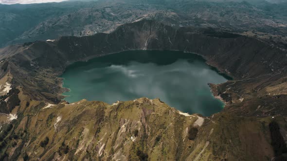 Cinematic aerial view over volcano landscape and crater lake during cloudy day in Ecuador