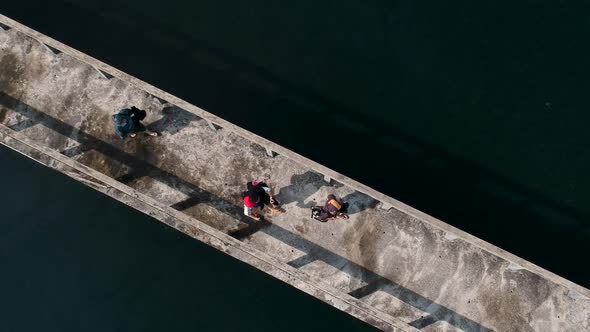 A aerial view looking done at people walking along a jetty out at sea