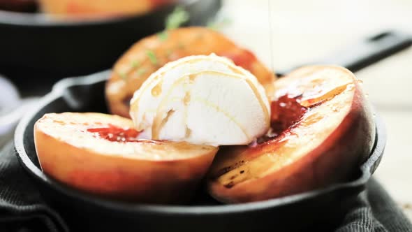 Organic grilled peaches with scoop of vanilla ice cream on a cast iron frying pan.