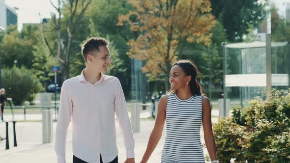 Multi-ethnic Couple Shyly Looking at Each Other While Walking the Street