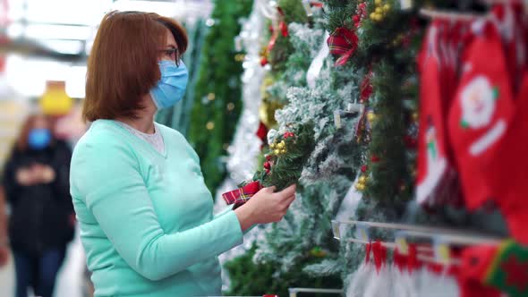 Woman in mask buying Christmas wreaths in supermarket