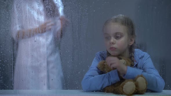 Nurse Making Injection to Sick Little Girl Hugging Teddybear Behind Rainy Window