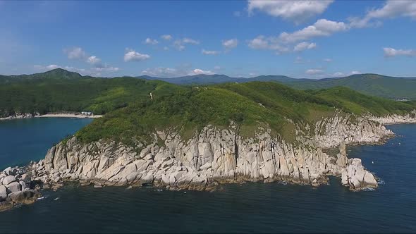 Aerial Shot Moving Along the Coastline of Deep Blue Sea Along a Dramatic Cliff Edge on Sunny Day
