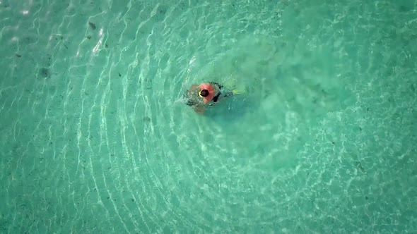 Aerial view of man and woman playing in turquoise sea.