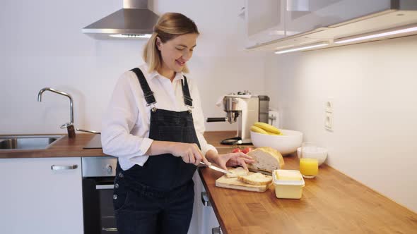 Pregnant Girl Making Sandwich in the Kitchen. Mom with a Pregnant Belly.