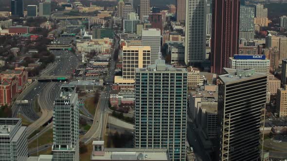 A high angle, medium pace tilt shot of the Atlanta Skyline with cars on the freeway on the side.