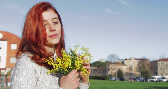 Young Girl Has Fun with a Bouquet of Yellow Mimosas in an Italian Park