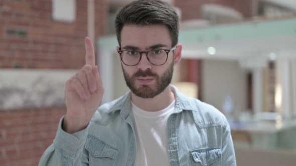 Portrait of Young Male Designer Saying No with Finger Sign