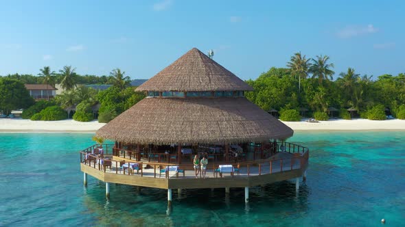 Aerial View on Young Couple in Water Restaurant on the Beach in Maldives Resort Island