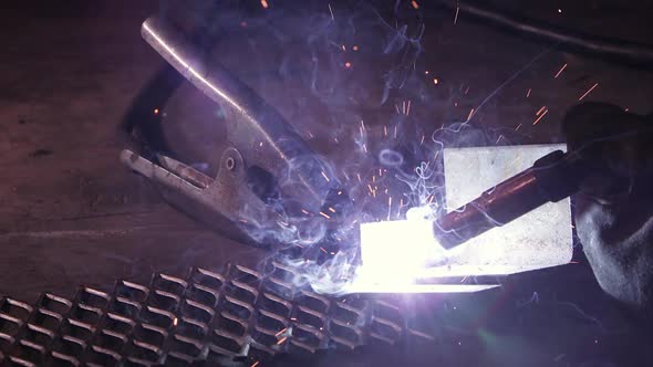 Close view of arc welder sparking as sparks shoot around.