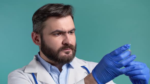 Doctor in Gloves Flicks Syringe Prior to Drug Injection to Collect and Release the Air Out of