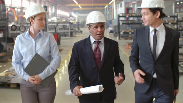 Executive Engineer Talking to Employees while Walking in Factory