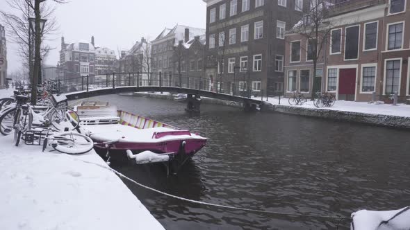 Rhine river flowing through snowy Leiden city centre, winter Netherlands city