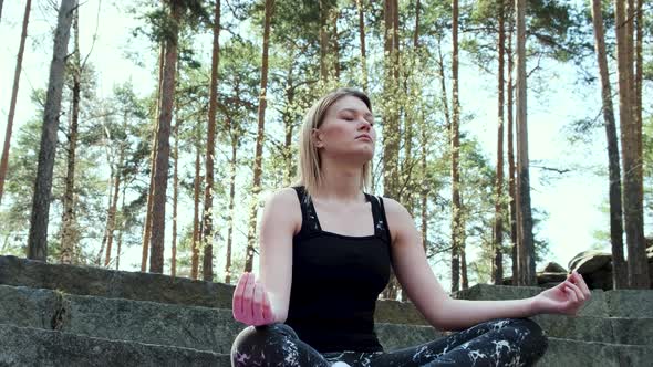 Happy woman meditating in forest outdoors