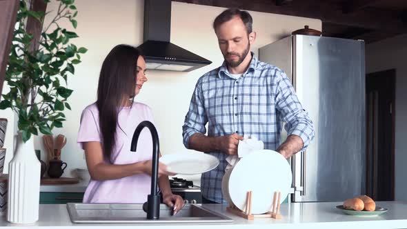 Couple washing dishes together in kitchen