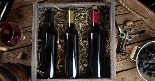 Bottles of Wine in a Wooden Box with Straw on the Table. On Wooden Background.