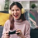 woman sitting on sofa with wearing headphones and holding joystick with playing games. - VideoHive Item for Sale