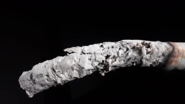 Smoke From a Lit Cigarette and a Drop of Ash Closeup on a Black Background in Closeup