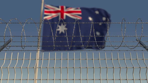 Blurred Waving Flag of Australia Behind Barbed Wire Fence