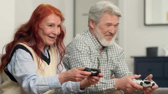 Senior Couple 5060 Years Old Playing Football Using Video Game at Home Sitting on the Couch