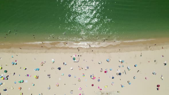 Colourful parasols and people relaxing at the beach in Sesimbra, Portugal