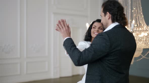 the Bride and Groom Dance on the Background of a Crystal Chandelier