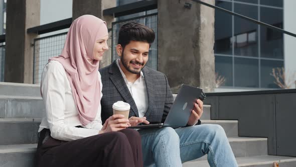 Muslim Man and Woman Using Laptop for Work on Stairs