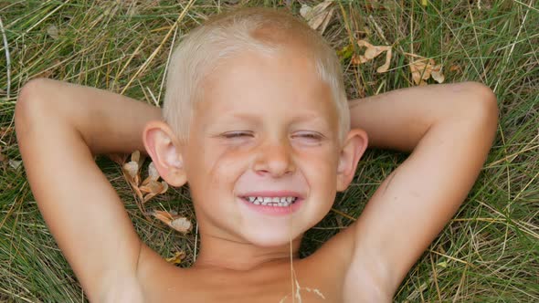 Portrait of a Funny Handsome Five Year Old Child Blond Boy with a Dirty Face Lying on the Grass with