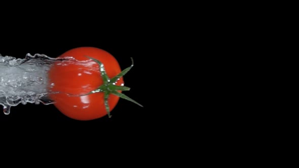 Red Cherry Tomato is Flying Horizontally on the Black Background with the Splash