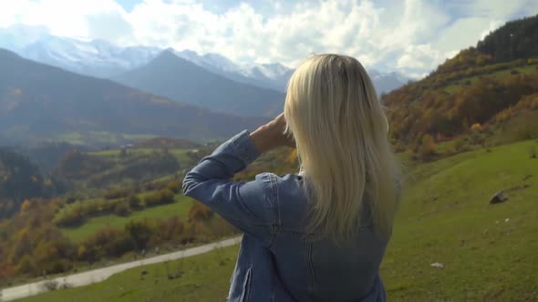 woman straightens her hair and enjoys the nature of autumn mountain landscape.
