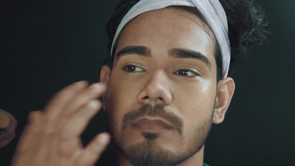 Close up of man's face and make up artist putting a face creme on his face