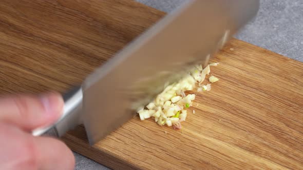 Chef Shreds Garlic with Kitchen Knife Cai Dao on Wooden Board