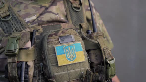 Ukrainian Military Man in Army Combat Uniform with Small Ukrainian Flag Using Walkietalkie