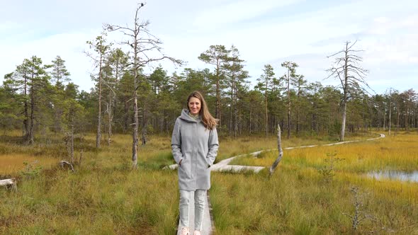 Young Happy Woman Walking on Wooden Boardwalk Through Bog Swamp Land